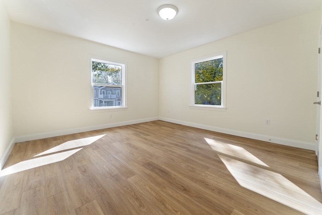 27 Perrin Street, Unit 1 Boston, MA 02119 - Photo 16 of 22 an empty room with wooden floor and windows