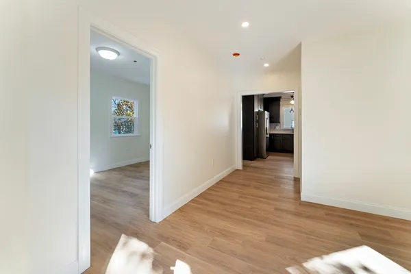 a view of a hallway with wooden floor and a living room