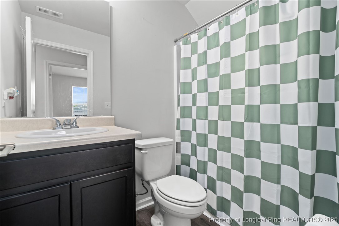 5926 Lowgrass Road Stedman, NC 28391 - Photo 5 of 39 a bathroom with a granite countertop toilet a sink and a mirror