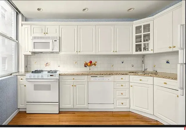 a kitchen with granite countertop white cabinets and white appliances