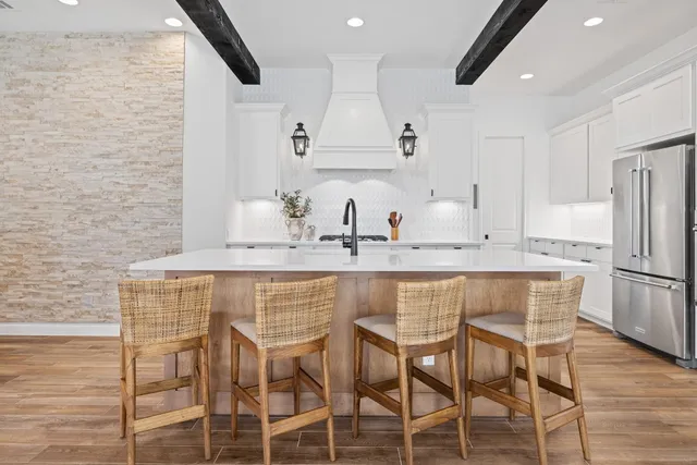 a kitchen with stainless steel appliances kitchen island granite countertop a dining table chairs sink and cabinets