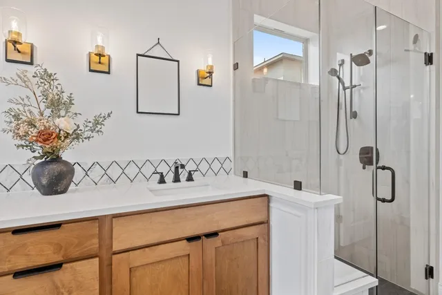 a bathroom with a granite countertop sink a mirror and shower
