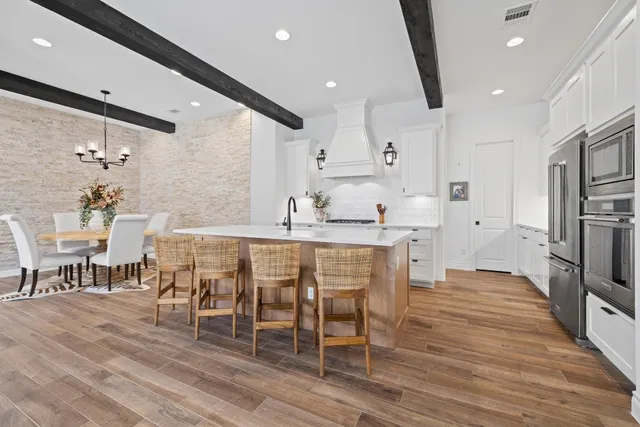 a kitchen with stainless steel appliances kitchen island granite countertop a table chairs sink and cabinets