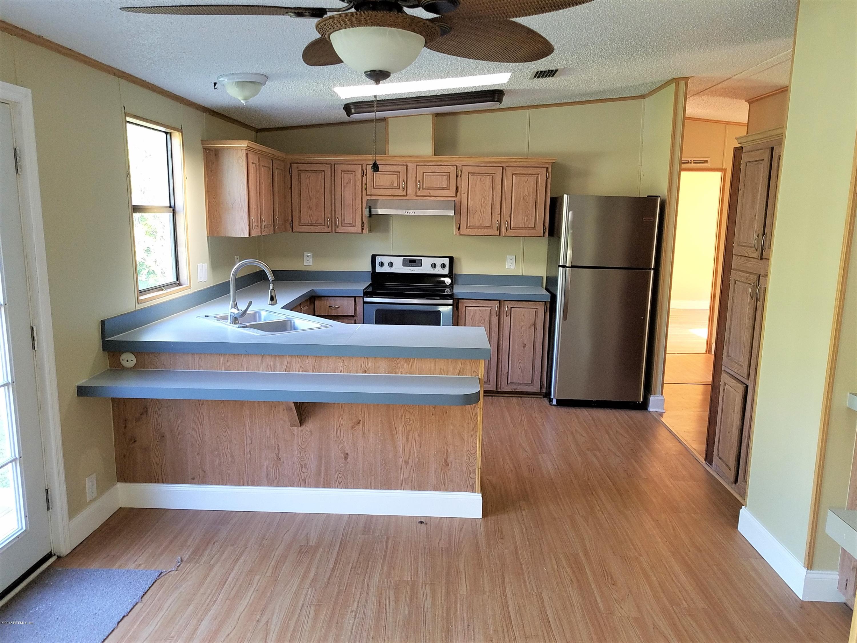 2801 Green Acres Road, Unit EXTENSION St. Augustine, FL 32084 - Photo 22 of 30 a kitchen with stainless steel appliances granite countertop a refrigerator a sink dishwasher a stove and white countertops with wooden floor