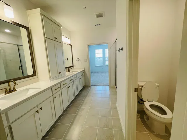 a bathroom with a double vanity sink a toilet and mirror