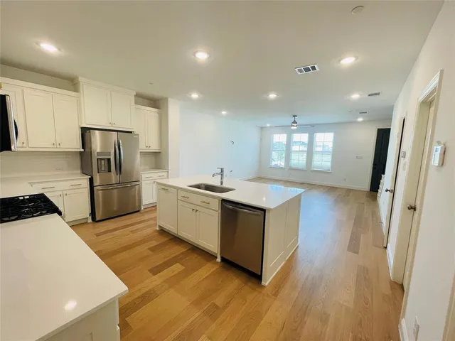 a kitchen with stainless steel appliances granite countertop a sink a microwave a refrigerator and a stove