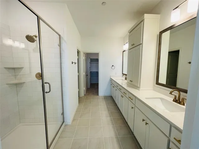 a large white bathroom with a double vanity sink a mirror and a shower