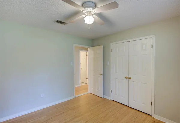 an empty room with closet and a chandelier fan