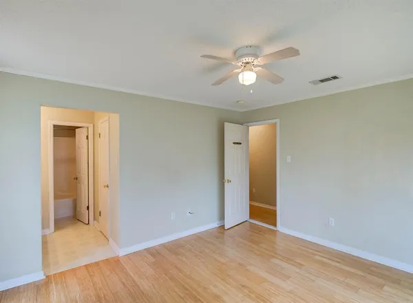 a view of an empty room with wooden floor and a ceiling fan