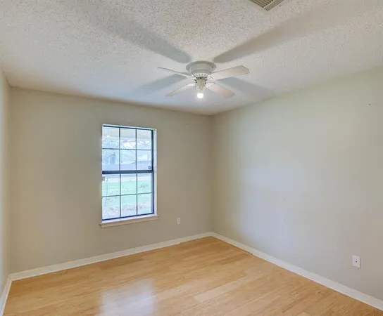 an empty room with windows and fan