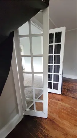 a view of an empty room with wooden floor and windows