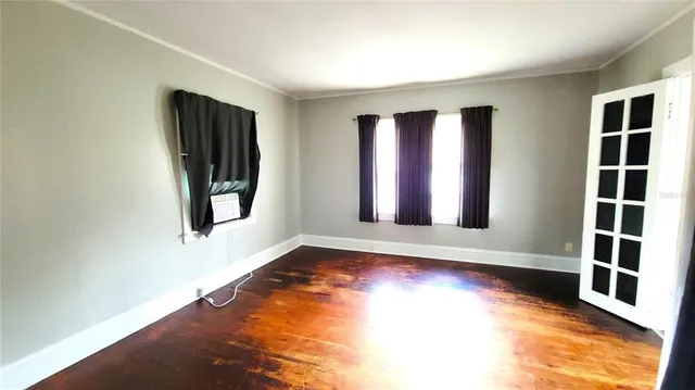 a view of an empty room with window and wooden floor