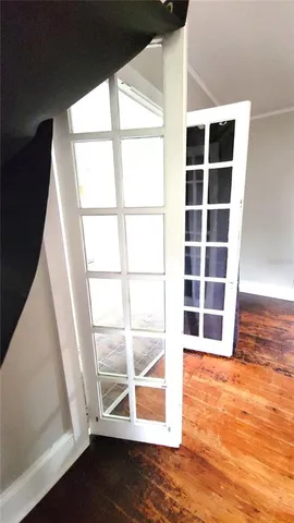 a view of an empty room with wooden floor and windows