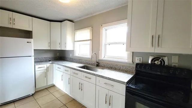 a kitchen with granite countertop white cabinets and a stove top oven