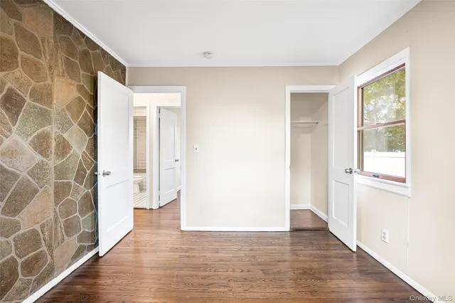 a view of a hallway with wooden floor and a bathroom