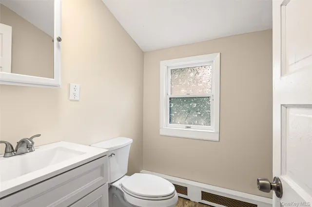 a bathroom with a granite countertop toilet a sink and a mirror