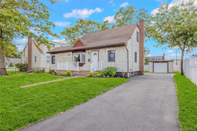 a view of a house with a yard plants and large tree