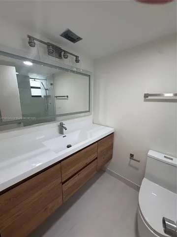 a bathroom with a sink mirror vanity and toilet