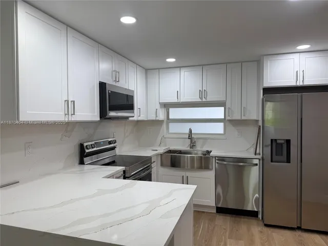 a kitchen with stainless steel appliances a stove a sink a microwave a refrigerator and cabinets