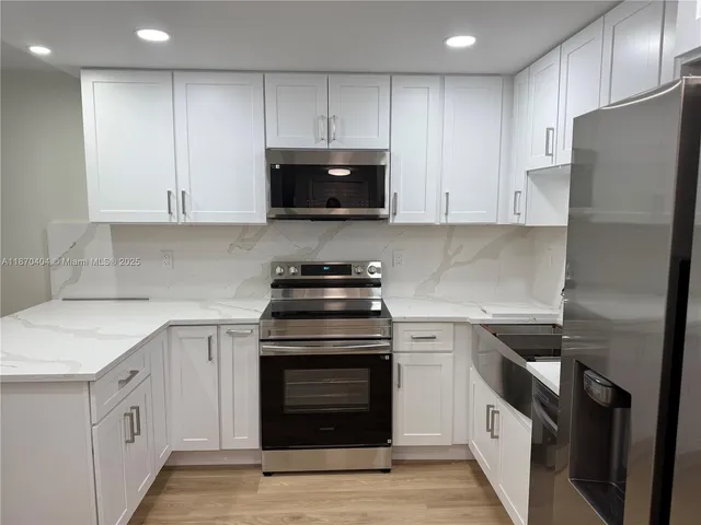 a kitchen with cabinets stainless steel appliances and sink