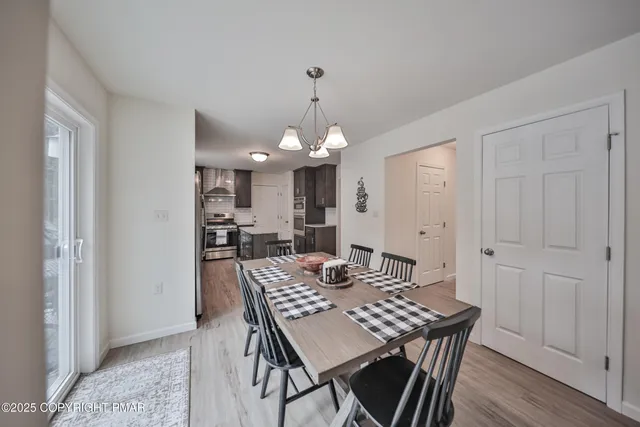 a open dining room with wooden floor a chandelier a wooden table and chairs
