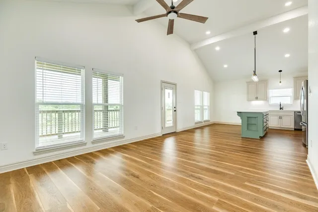 a view of an empty room with a window and wooden floor
