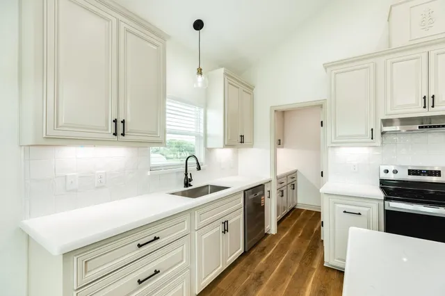 a kitchen with stainless steel appliances a sink stove and cabinets