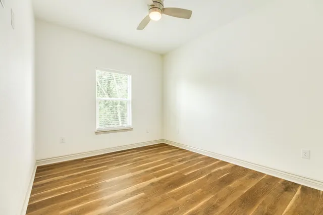 an empty room with a window and a ceiling fan
