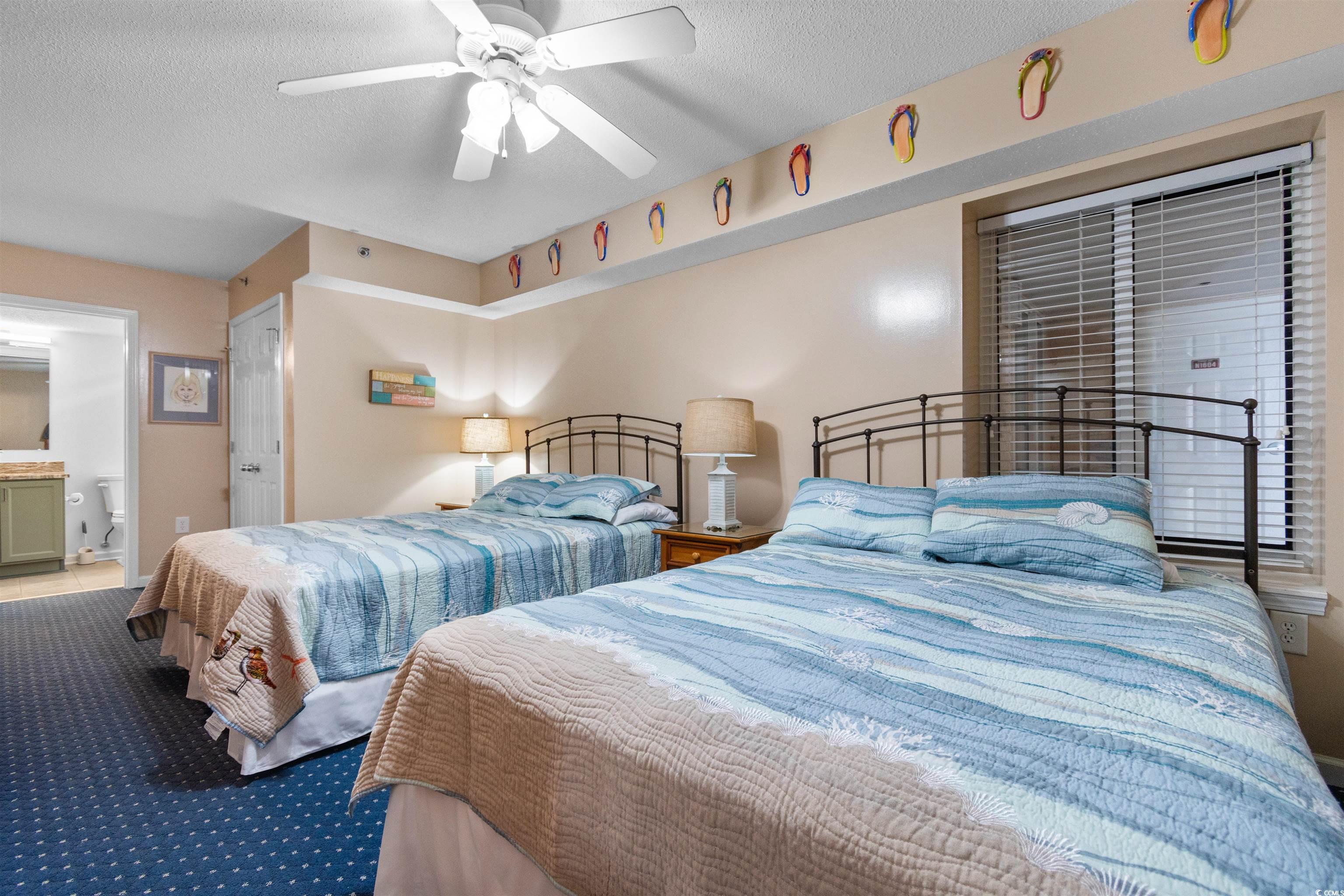 1625 South Ocean Boulevard, Unit 1603 North Myrtle Beach, SC 29582 - Photo 17 of 39 Carpeted bedroom featuring a textured ceiling, a ceiling fan, and ensuite bath