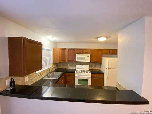 a kitchen with stainless steel appliances a sink a stove a microwave a counter top and a refrigerator