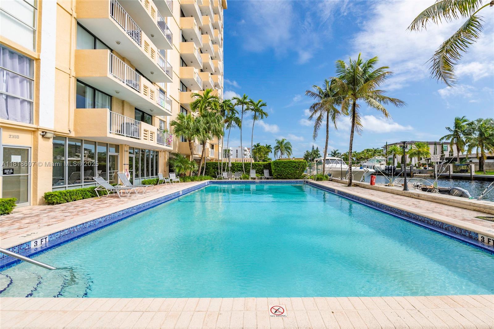 2350 Northeast 135th Street, Unit 1006 North Miami, FL 33181 - Photo 28 of 29 a swimming pool with outdoor seating and yard
