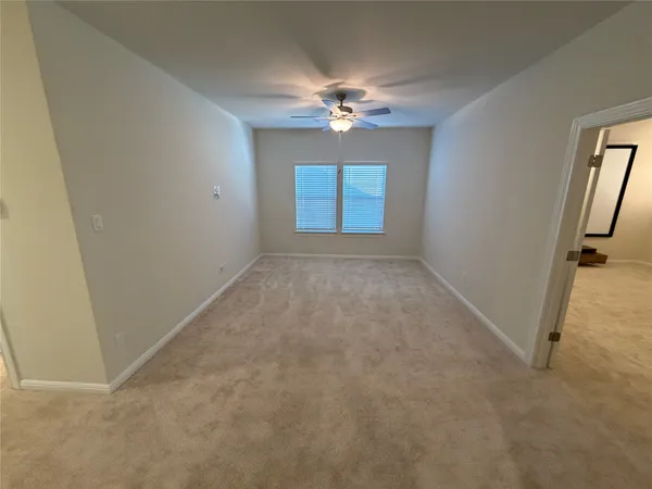 an empty room with windows and fan