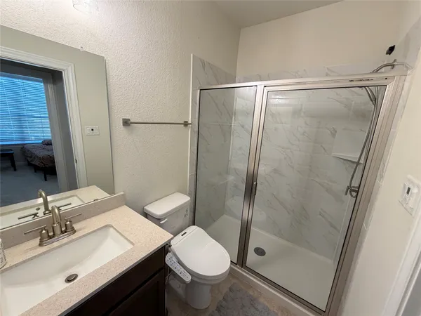 a bathroom with a shower sink vanity mirror and toilet