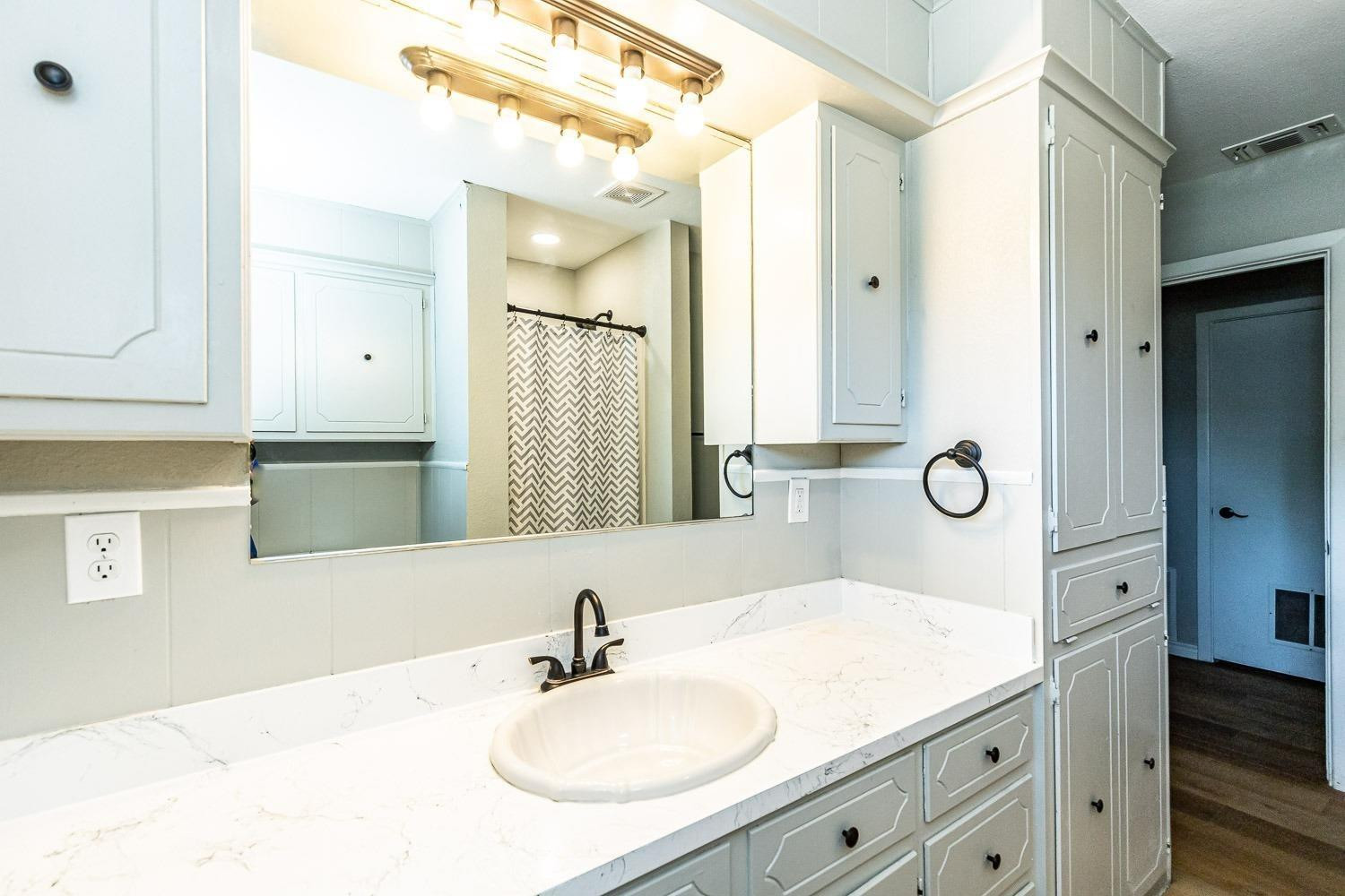 3411 42nd Street Lubbock, TX 79413 - Photo 18 of 33 a bathroom with a sink and a mirror