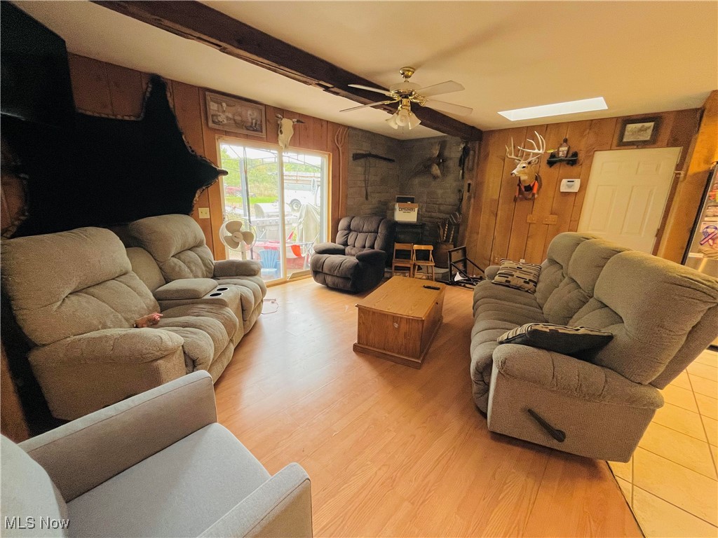 2687 Griggs Road Jefferson, OH 44047 - Photo 17 of 41 Living room featuring ceiling fan, light wood-type flooring, wooden walls, and beam ceiling