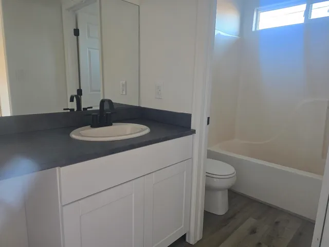a bathroom with a granite countertop sink toilet and a mirror