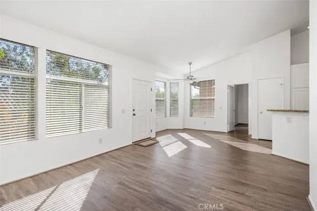 a view of an empty room with a window and wooden floor