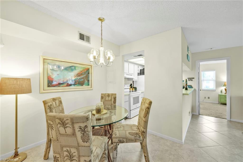 4287 27th Court Southwest, Unit 202 Naples, FL 34116 - Photo 12 of 17 a view of a dining room with furniture and chandelier