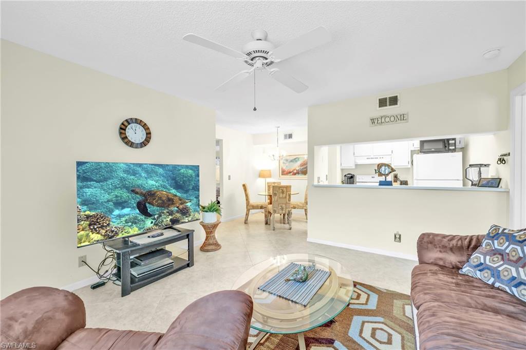 4287 27th Court Southwest, Unit 202 Naples, FL 34116 - Photo 15 of 17 a living room with furniture and a chandelier