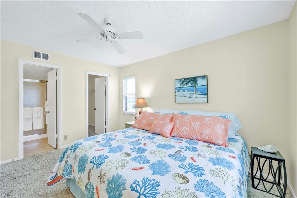 4287 27th Court Southwest, Unit 202 Naples, FL 34116 - Photo 9 of 17 a bedroom with a large bed and a chandelier