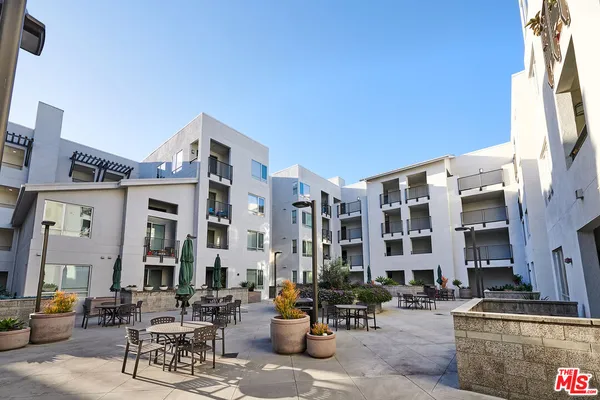 a front view of multi story residential apartment building with yard and parking