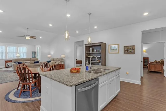 a kitchen with stainless steel appliances granite countertop a sink a stove a dining table and chairs