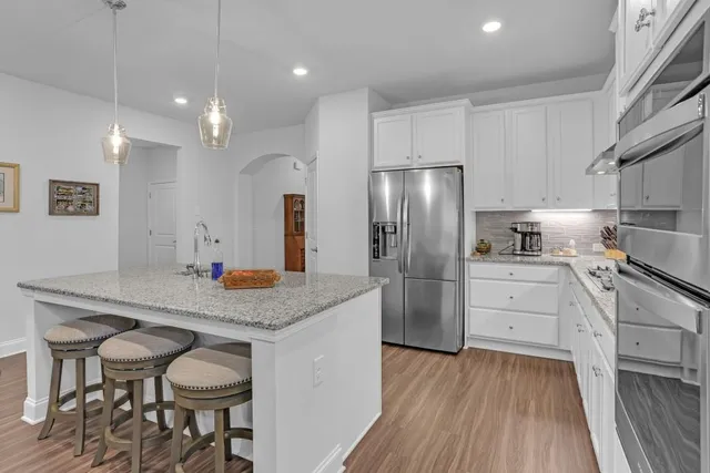 a kitchen with stainless steel appliances granite countertop a refrigerator a sink and white cabinets