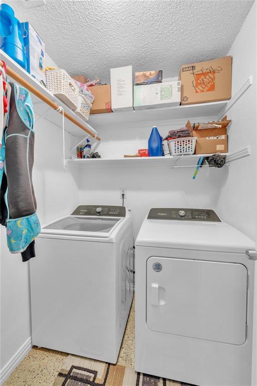 7613 Clover Lane Watauga, TX 76148 - Photo 20 of 36 Laundry room with dark aggregate flooring, a textured ceiling, and washing machine and dryer