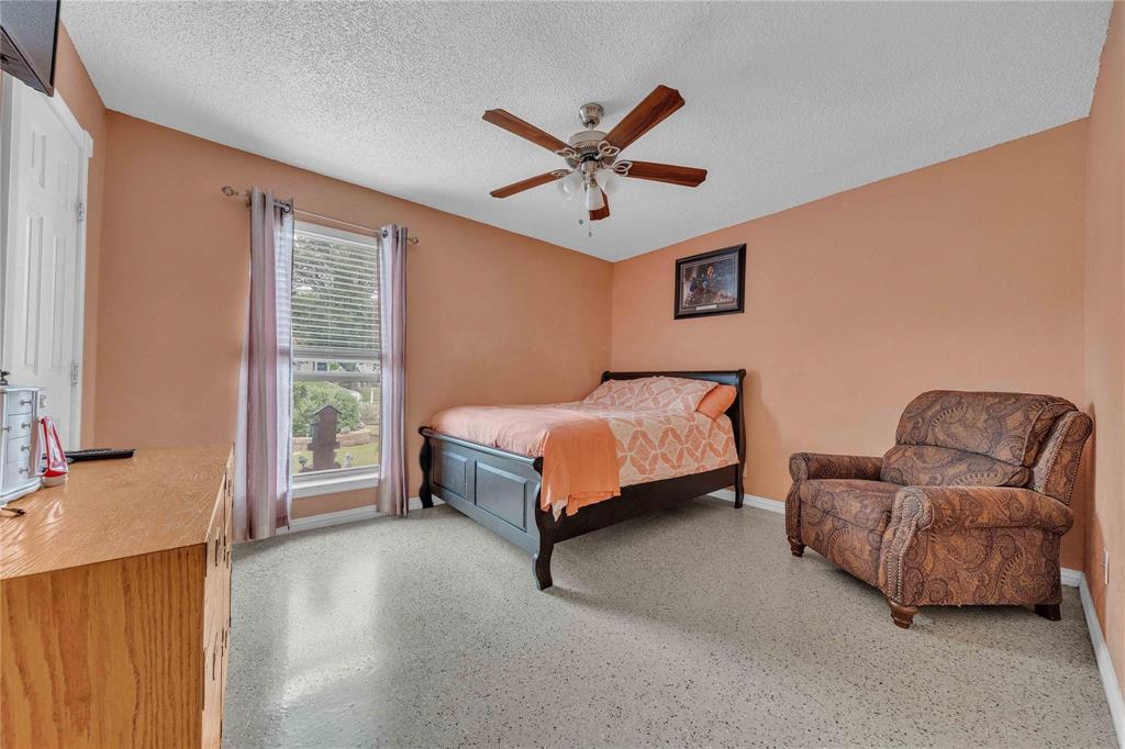 7613 Clover Lane Watauga, TX 76148 - Photo 22 of 36 Bedroom with dark aggregate flooring, a ceiling fan, and a textured ceiling