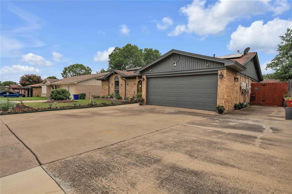 7613 Clover Lane Watauga, TX 76148 - Photo 4 of 36 Ranch-style house featuring solar panels, concrete driveway, brick siding, an attached garage, and a gate