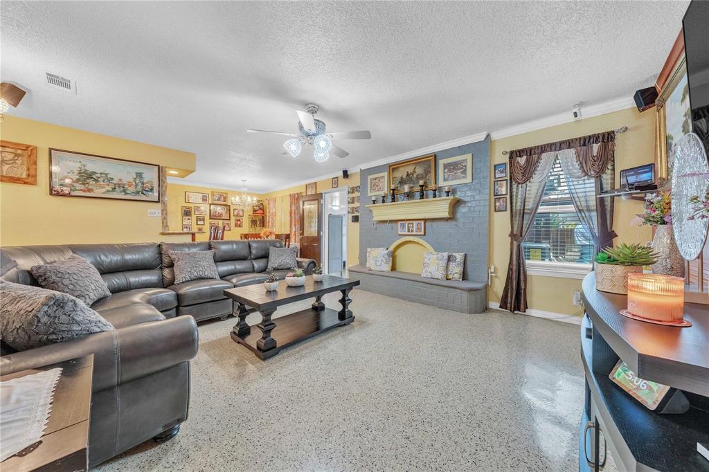 7613 Clover Lane Watauga, TX 76148 - Photo 9 of 36 Living area with speckle patterned floor, ceiling fan, a textured ceiling, ornamental molding, and hanging lights