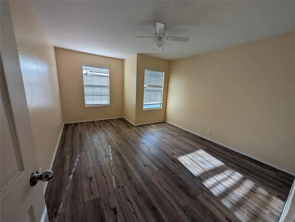 an empty room with wooden floor and fan