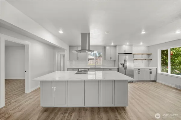 a large white kitchen with kitchen island a sink stainless steel appliances and cabinets