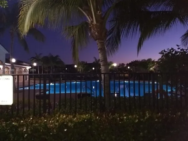 a night view of backyard with swimming pool and patio
